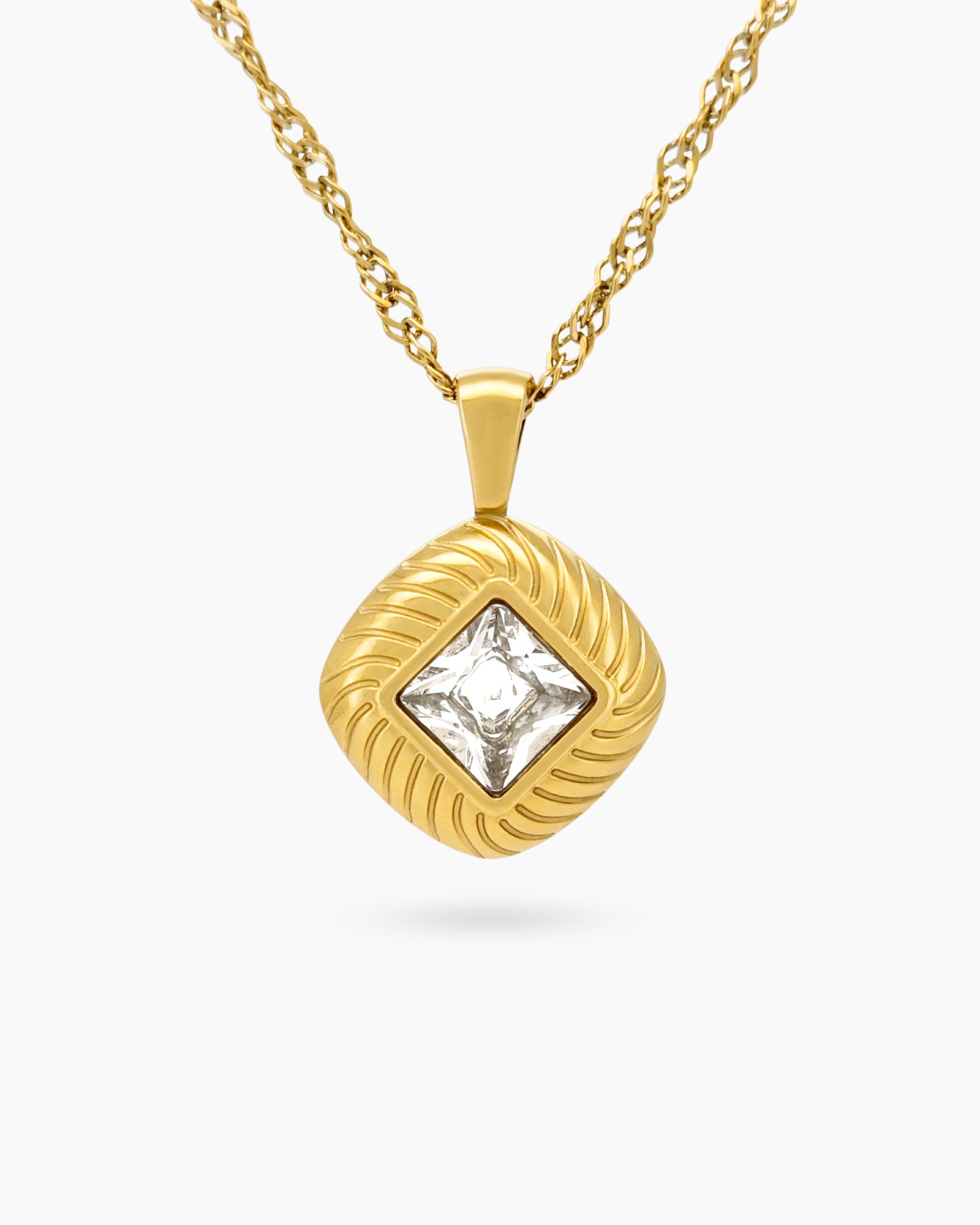 A white necklace with a square-cut pendant in a sculptural, gold-tone setting with a twisted rope chain