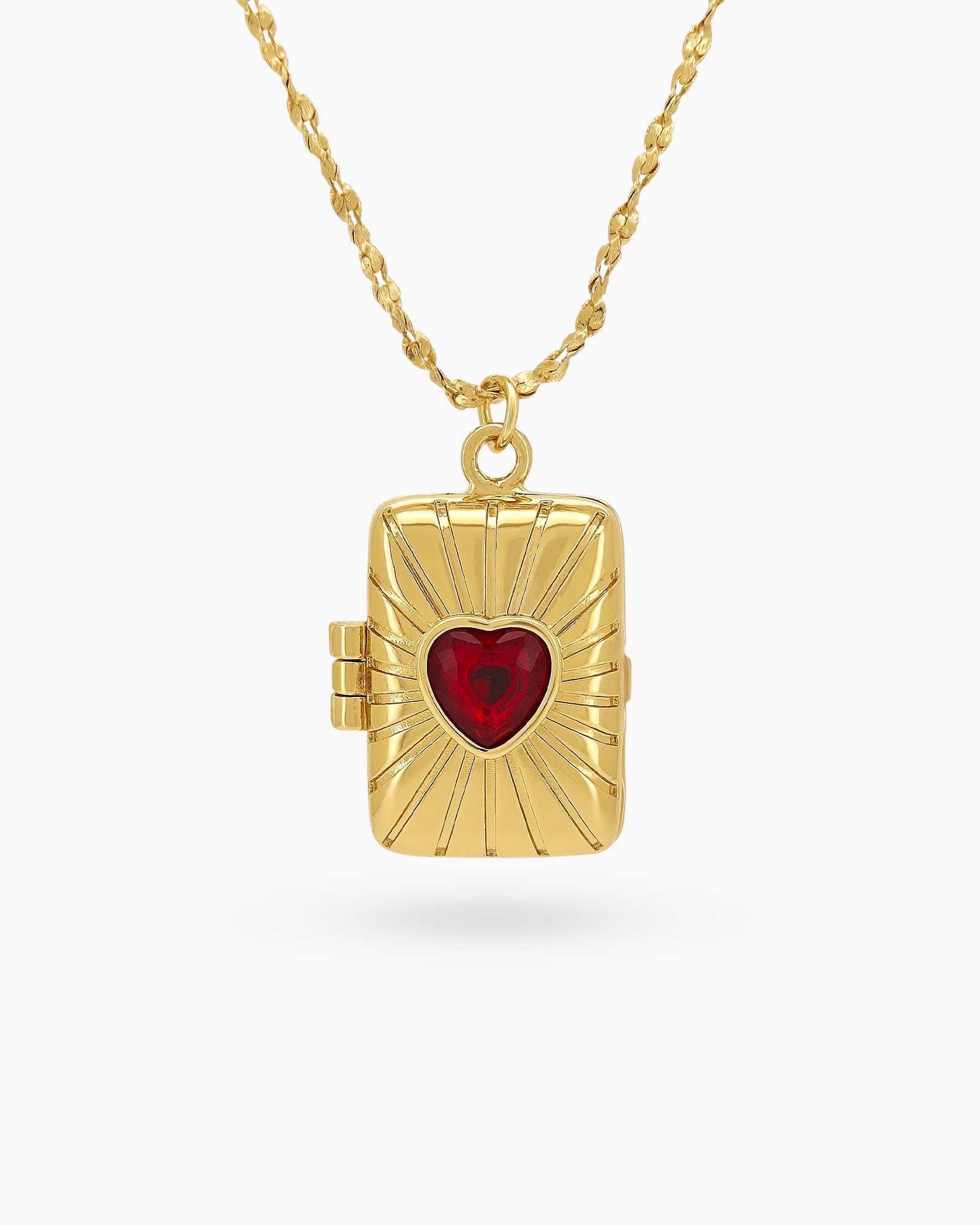 A rectangular locket with sunburst detailing that opens to a hidden space, with a red heart zircon