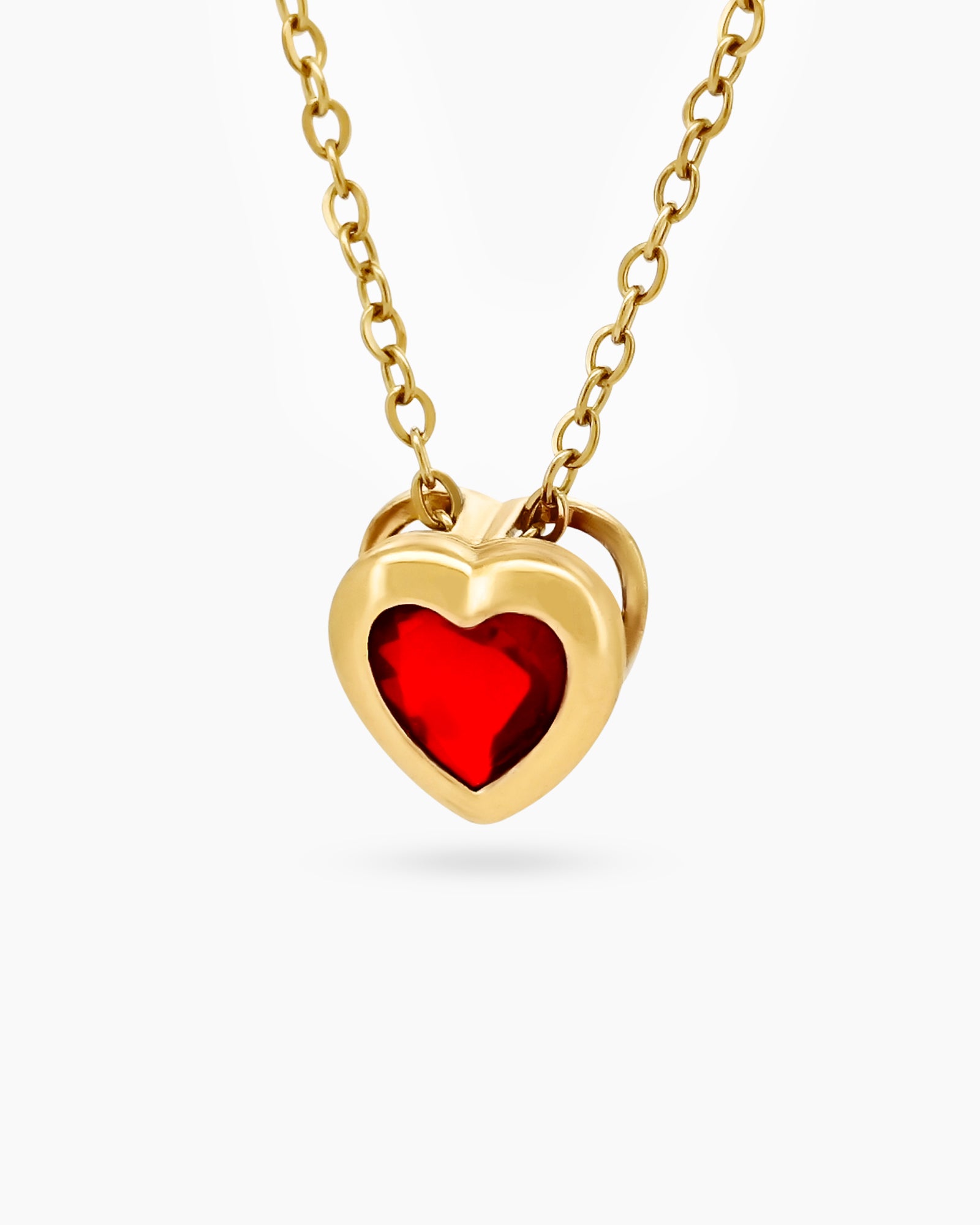 A Red necklace with a vibrant heart-shaped zircon encased in a smooth, gold-toned bezel