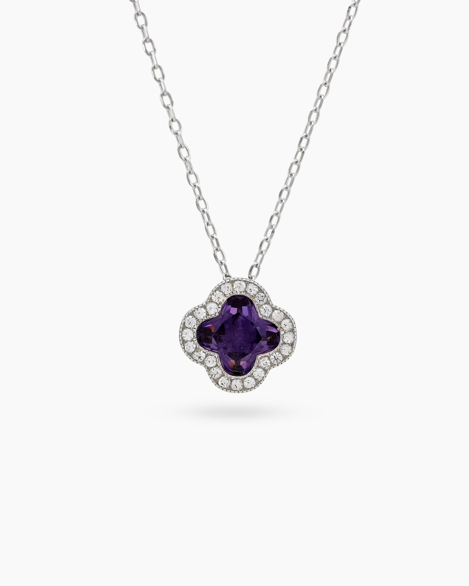 A purple necklace with a clover pendant outlined in pavé zircons and a faceted four-petal center stone