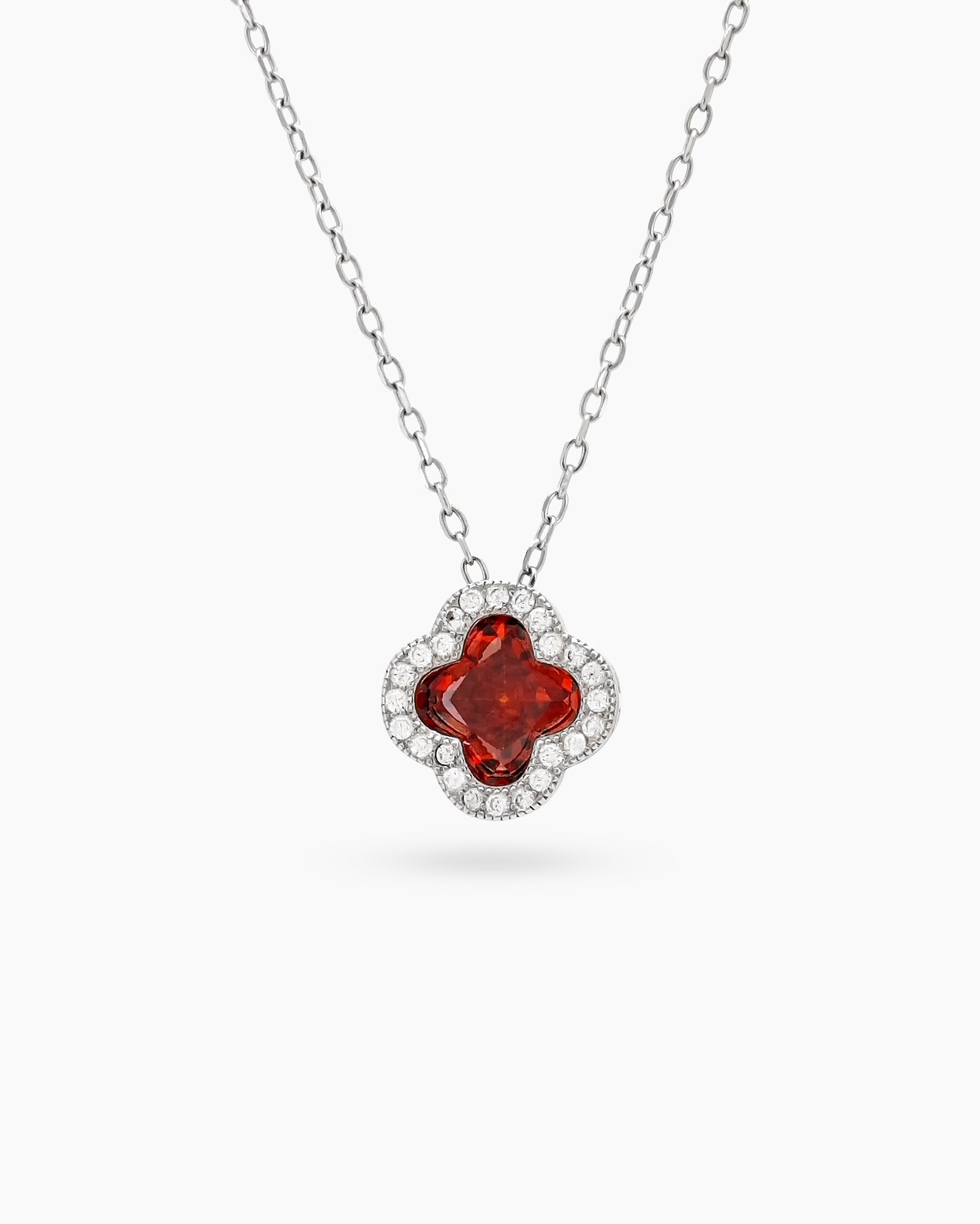A red necklace with a clover pendant outlined in pavé zircons and a faceted four-petal center stone
