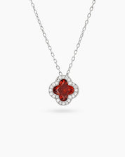 A red necklace with a clover pendant outlined in pavé zircons and a faceted four-petal center stone