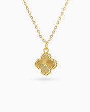A gold-plated sterling silver necklace with a clover-shaped pendant and a sunburst-engraved surface