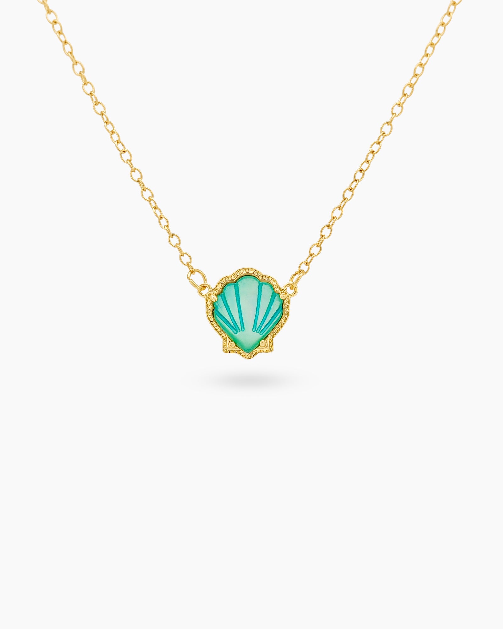 A seafoam necklace with a hand-engraved resin shell pendant in a fine gold-tone bezel on a dainty chain