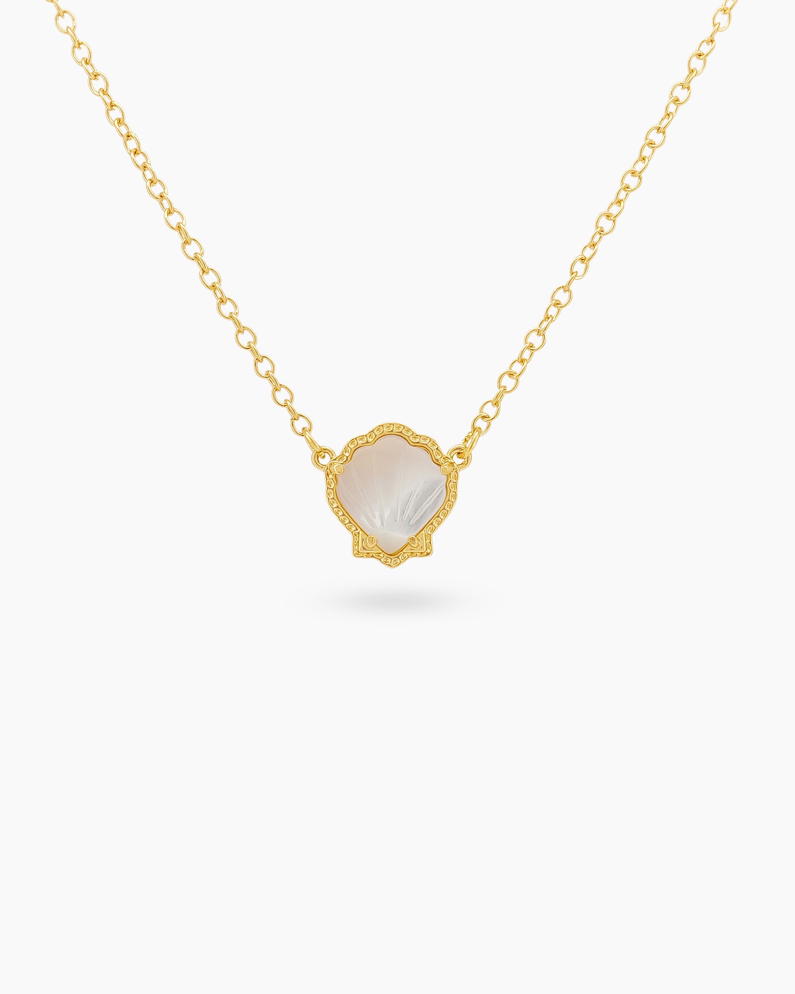 A white necklace with a hand-engraved resin shell pendant in a fine gold-tone bezel on a dainty chain