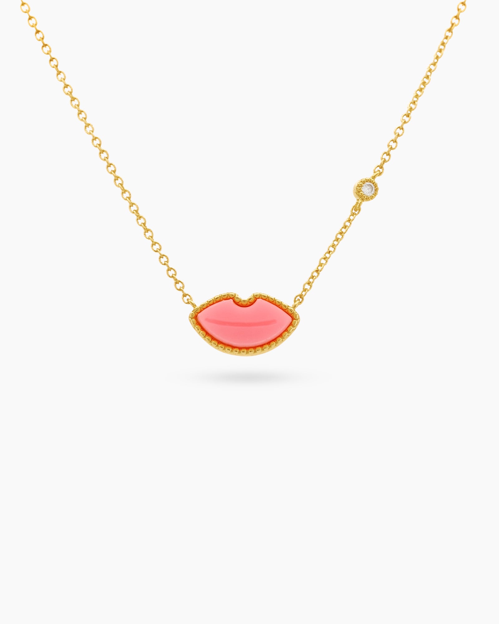 A necklace with a vibrant pink lips charm made from hand-engraved resin on a delicate gold-tone chain