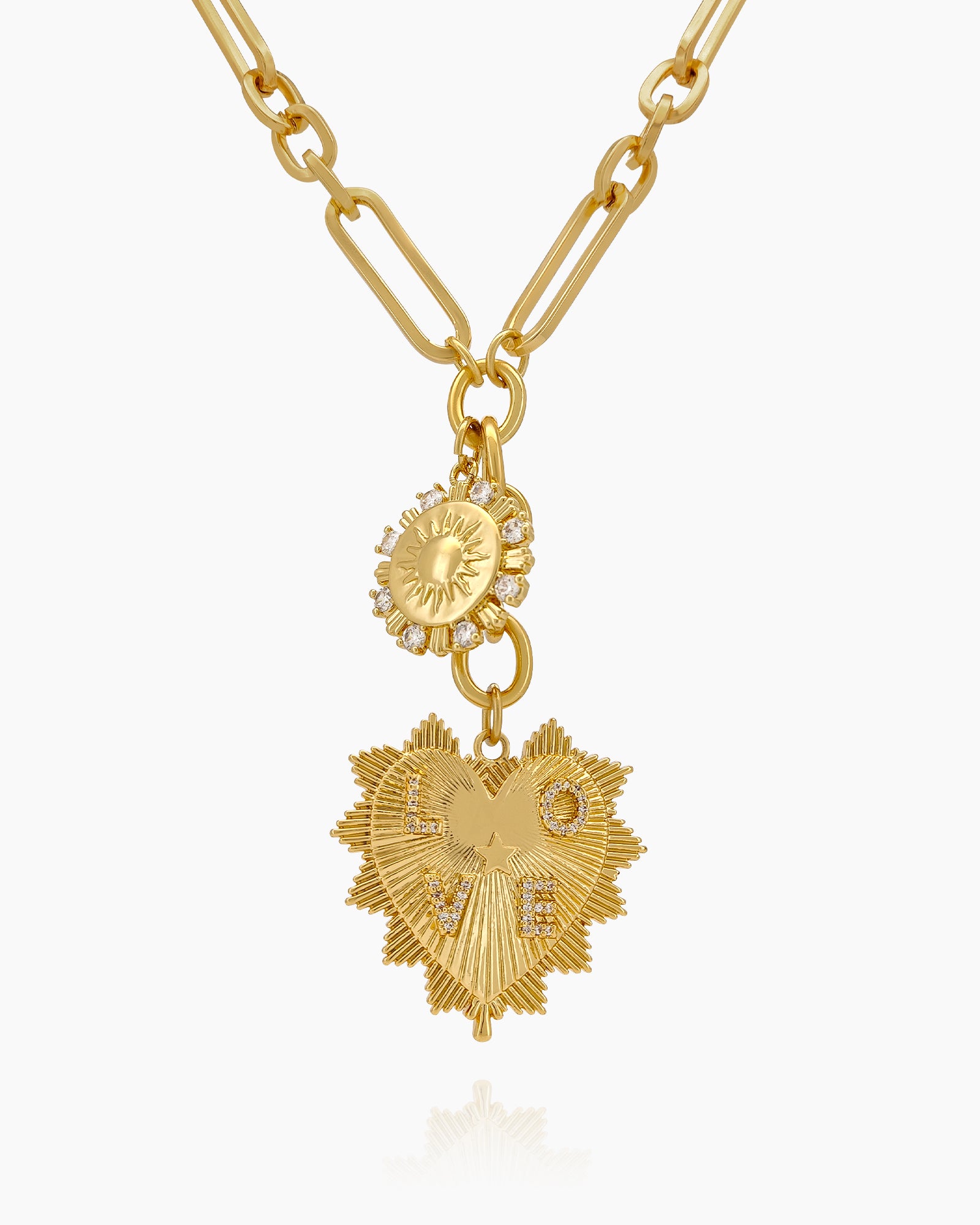 A necklace with a sunburst charm and a radiant, heart-shaped pendant on an elongated gold link chain