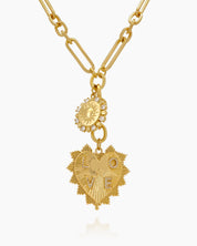 A necklace with a sunburst charm and a radiant, heart-shaped pendant on an elongated gold link chain