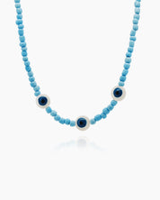 A necklace of soft matte sky-blue beads with three white enamel evil eye accents for a pop of color