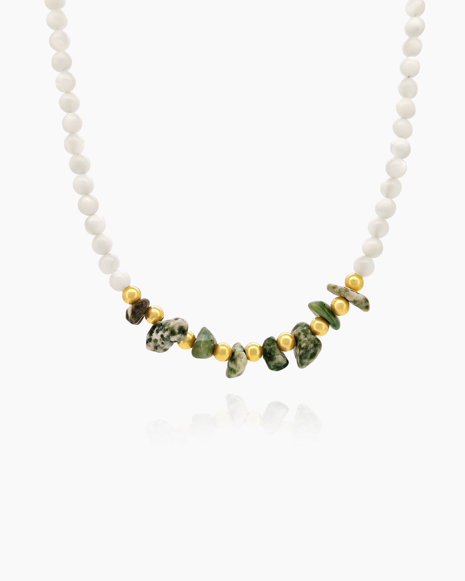 A necklace of soft matte white beads accented by a cluster of irregular green jade chips