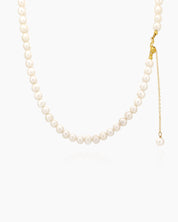 A necklace with a classic strand of lustrous freshwater pearls and a delicate gold-toned chain drop