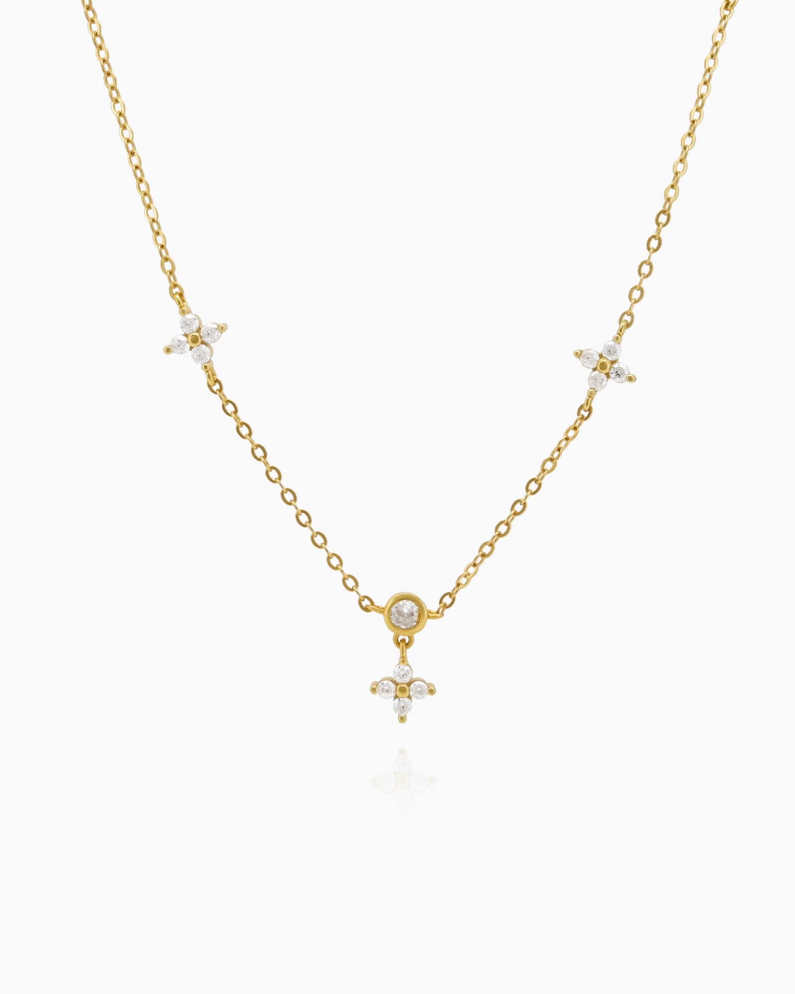 A delicate gold-tone chain necklace dotted with bezel-set round stones and tiny four-petal floral clusters