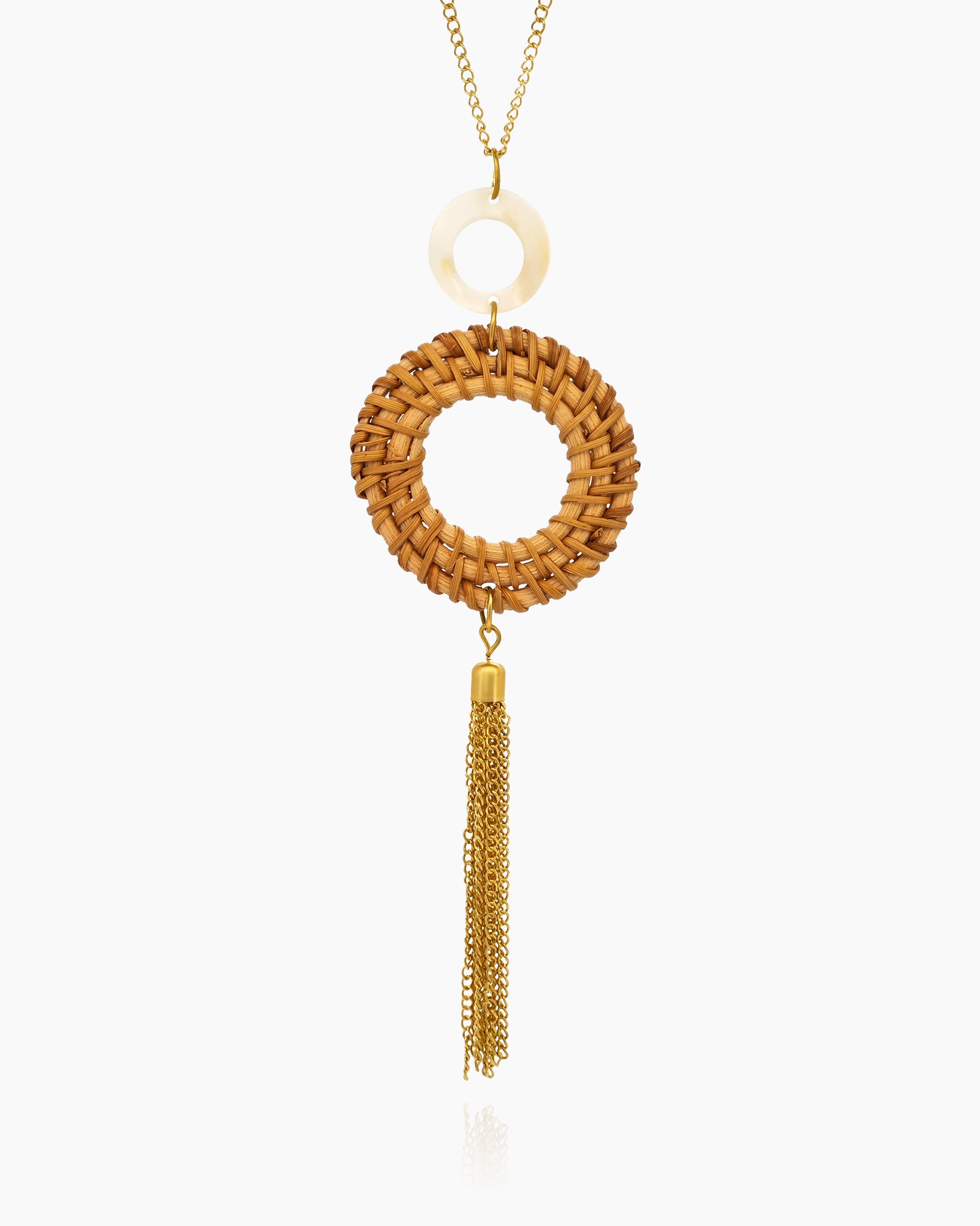 A necklace with a handwoven rattan ring, a mother of pearl disc, and a cascade of golden tassel chains
