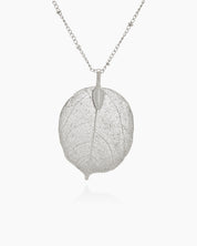 A silver necklace with a delicate leaf pendant featuring intricate vein patterns on a slim, textured chain