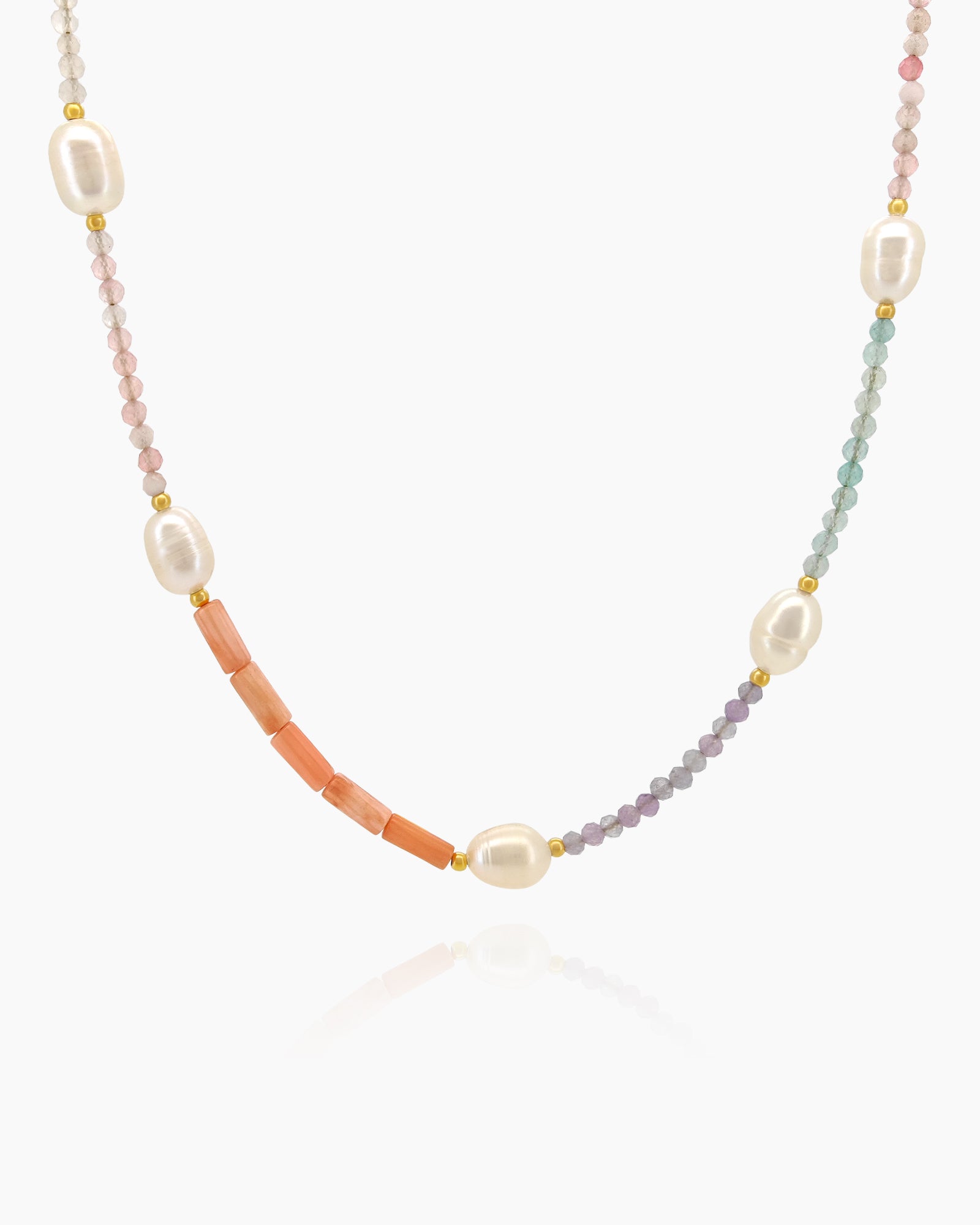 A beaded necklace with coral stones, freshwater pearls, and crystallized quartz beads in artful segments