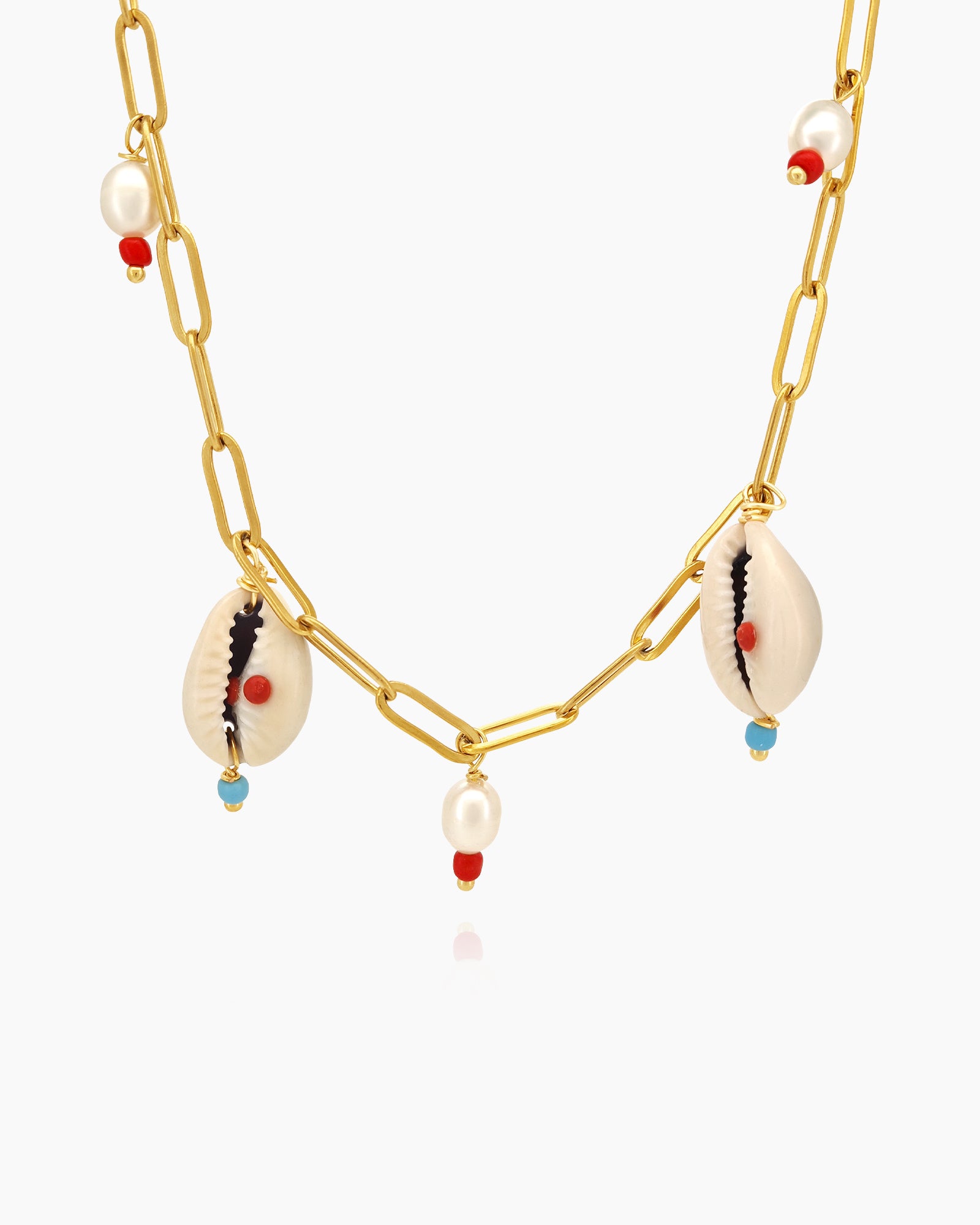 A necklace with cowrie shells, freshwater pearls, and beads on a bold gold link chain for a seaside flair