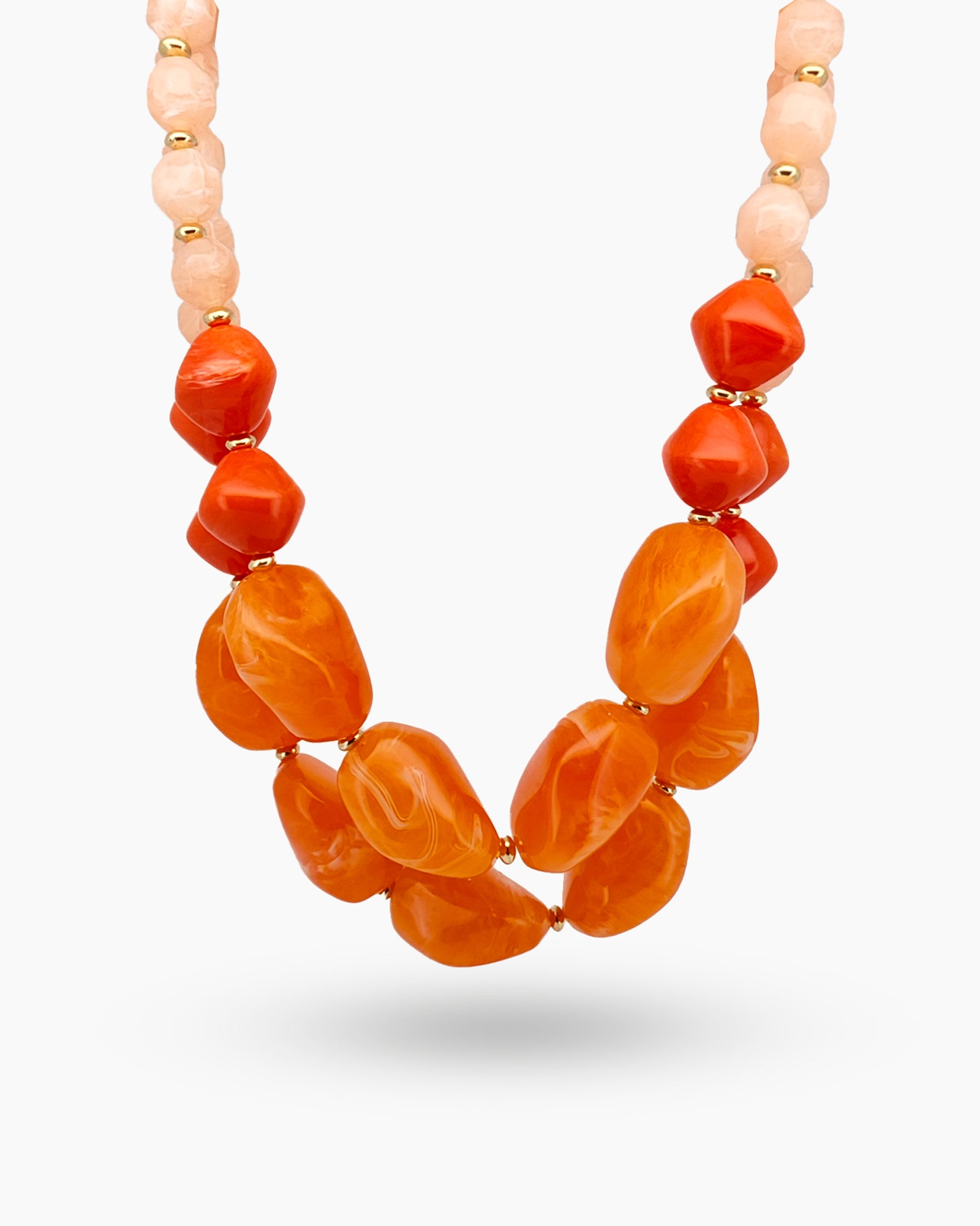 A necklace with a blend of polished peach and mandarin-toned beads that gracefully graduate in size