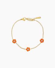 An orange bracelet with a delicate gold-tone chain adorned with a glossy enamel daisy