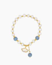 A hand-strung bracelet with creamy freshwater pearls, aquamarine crystals, and a mother-of-pearl charm