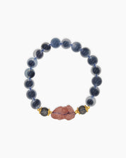 A bracelet of smooth blue agate stones with a central carved pink charm and golden accents