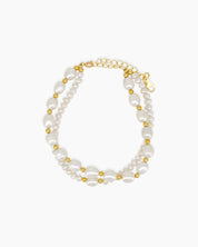 A bracelet with two rows of freshwater pearls in contrasting sizes, interspersed with golden beads