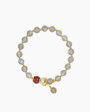 A bracelet of hand-strung natural moonstone beads with a single strawberry quartz bead and golden accents