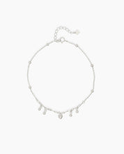 An adjustable 925 sterling silver anklet with a delicate chain, polished beads, and mini charms