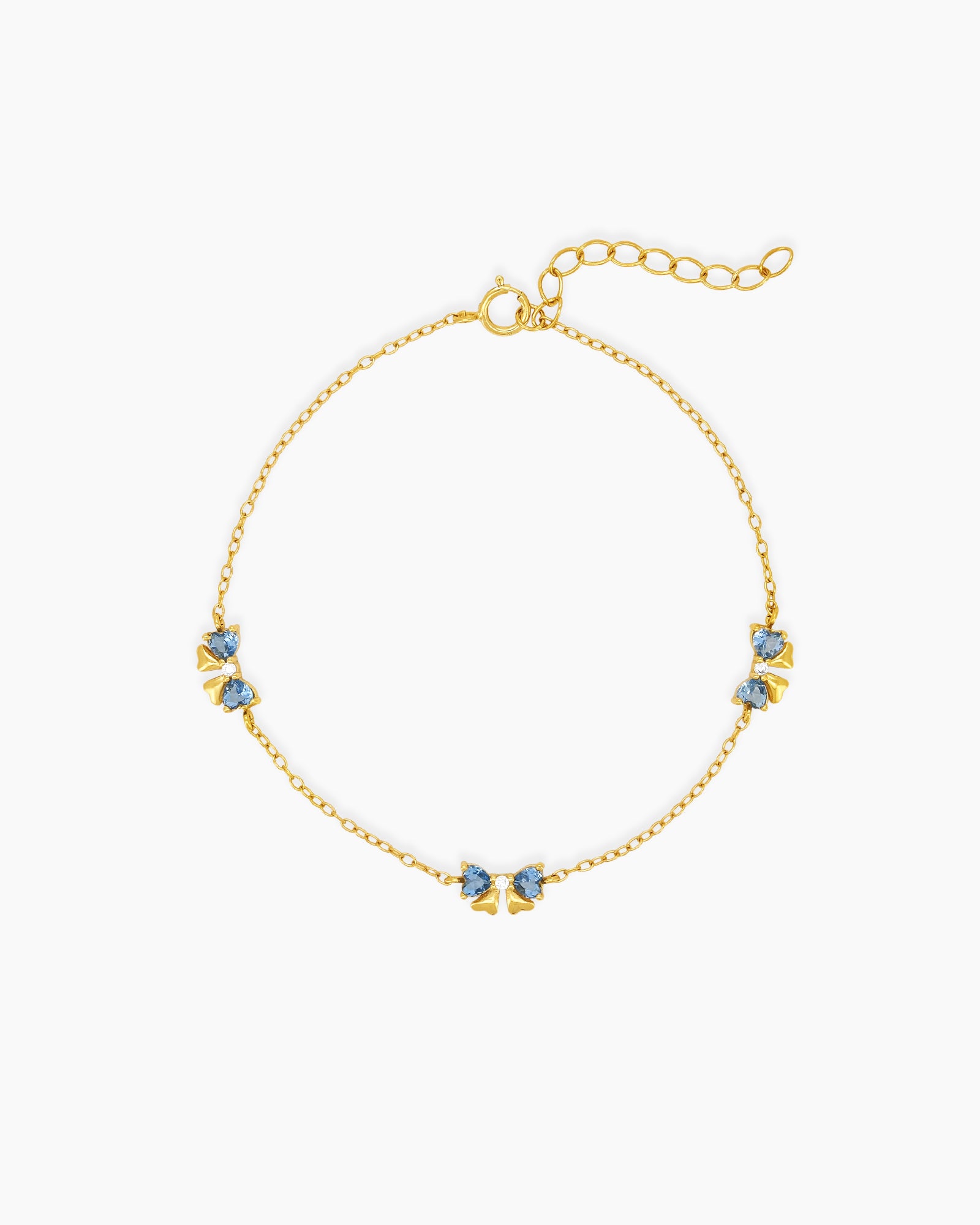 A dainty gold-toned bracelet with three tiny bows crafted from sparkling blue heart-cut zircons