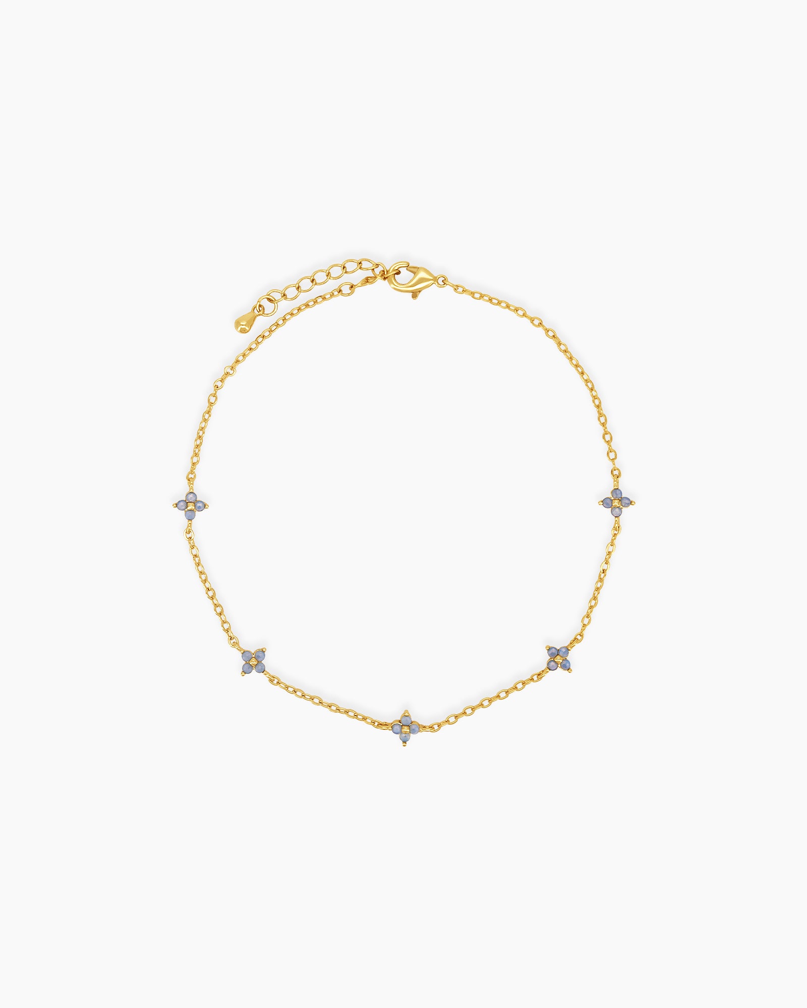 An anklet with tiny blue flower-shaped stations set along a fine gold-tone chain for a feminine look