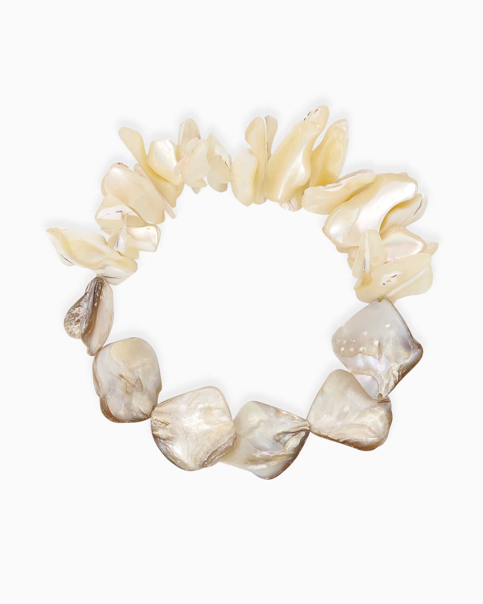 A stretch bracelet of irregular shell fragments in soft ivory, cream, and sand tones for an earthy look