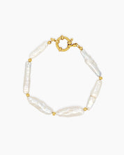 A bracelet of elongated baroque pearls with soft, iridescent sheen, accented by delicate gold-toned beads