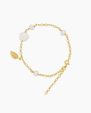 A bracelet with a finely sculpted white rose centerpiece, framed by freshwater pearls and a golden leaf accent