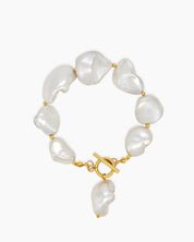 A bracelet of shimmering baroque pearls nestled between dainty gold beads, with a bold T-bar toggle clasp