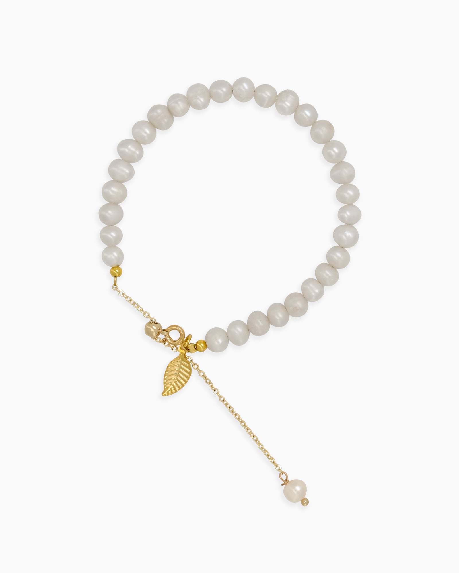 A bracelet of luminous round pearls with gold-toned accents and a delicate dangling leaf charm
