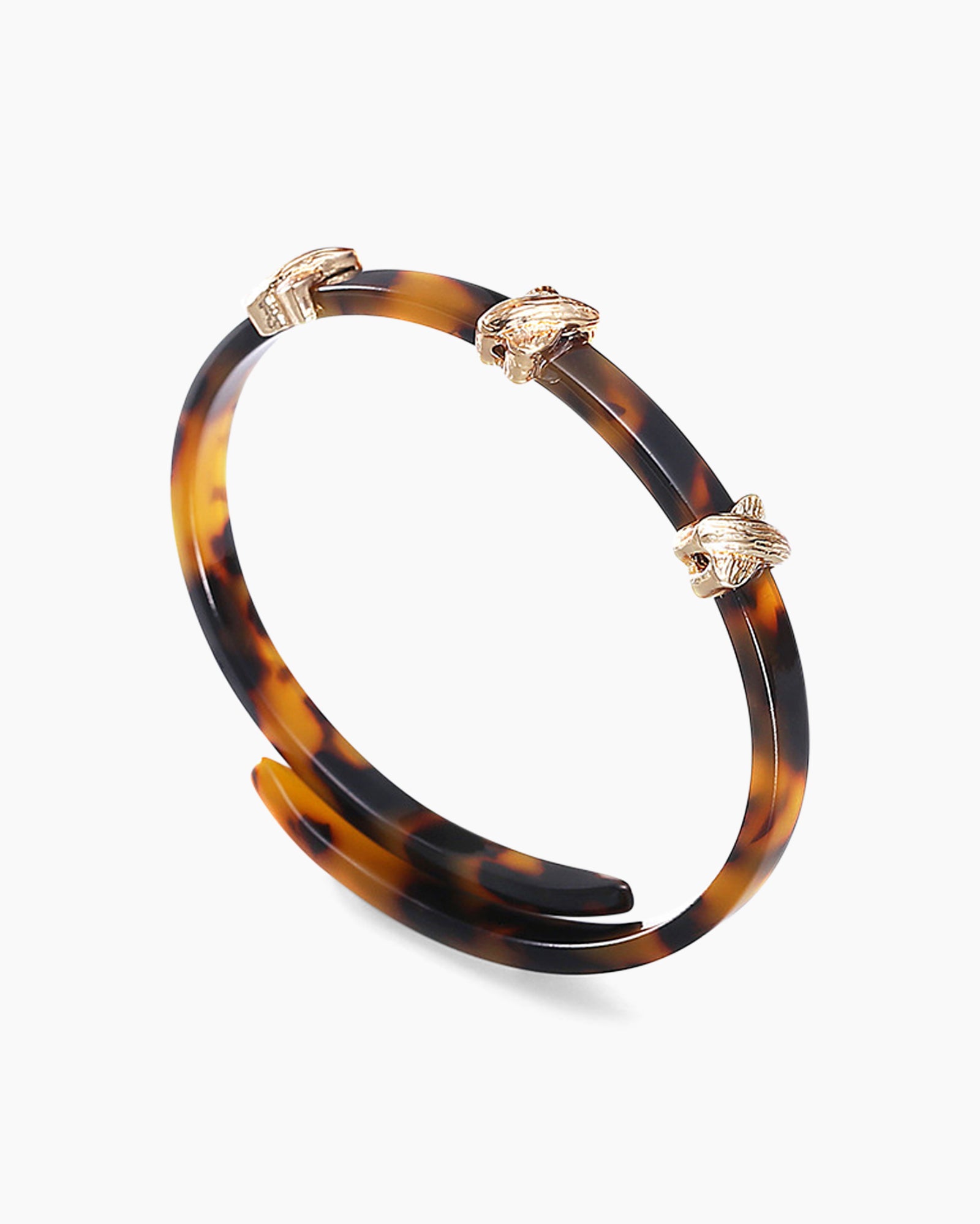 A double-wrapped bangle in high-gloss acrylic with a tortoiseshell effect and polished cross details