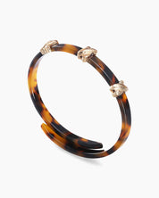 A double-wrapped bangle in high-gloss acrylic with a tortoiseshell effect and polished cross details