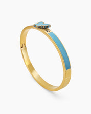 A blue hinged bangle with a sleek gold-tone design, vibrant enamel band, and a butterfly centerpiece