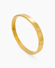 A gold-plated bangle with slim, geometric lines and delicate stone accents for a refined sparkle