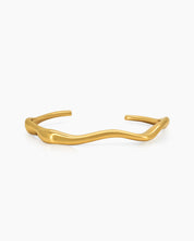 A gold open bangle with soft, wavy curves that wrap gently around the wrist for a refined look