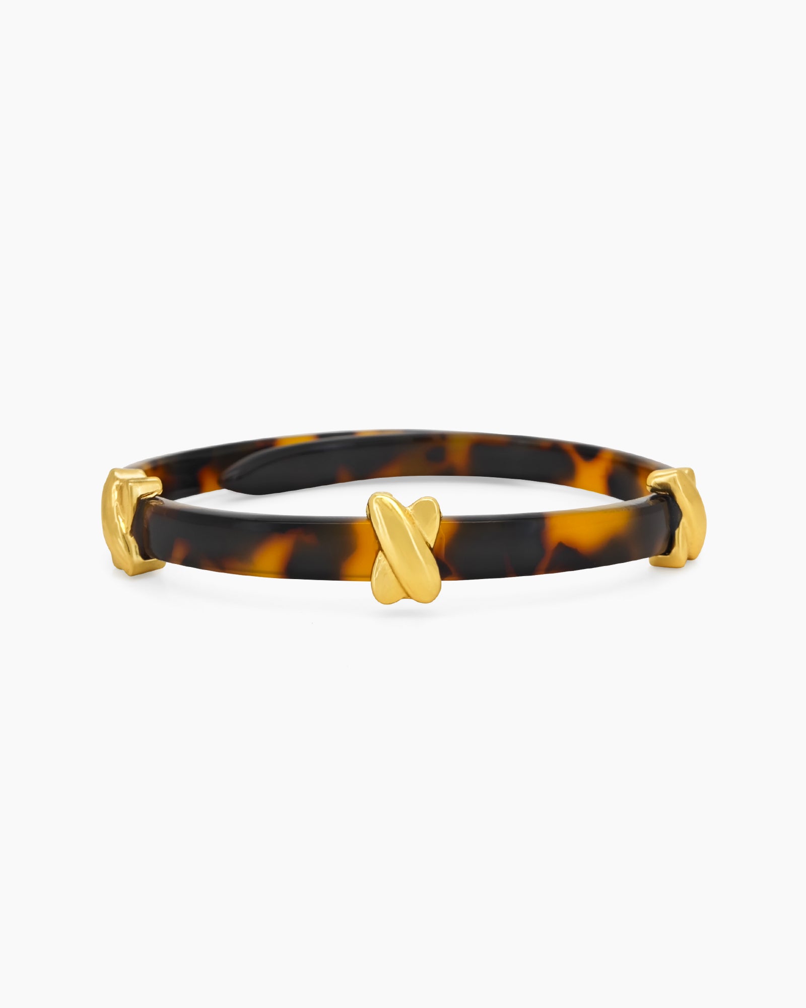 A double-wrapped bangle in high-gloss acrylic with a tortoiseshell effect and polished cross details