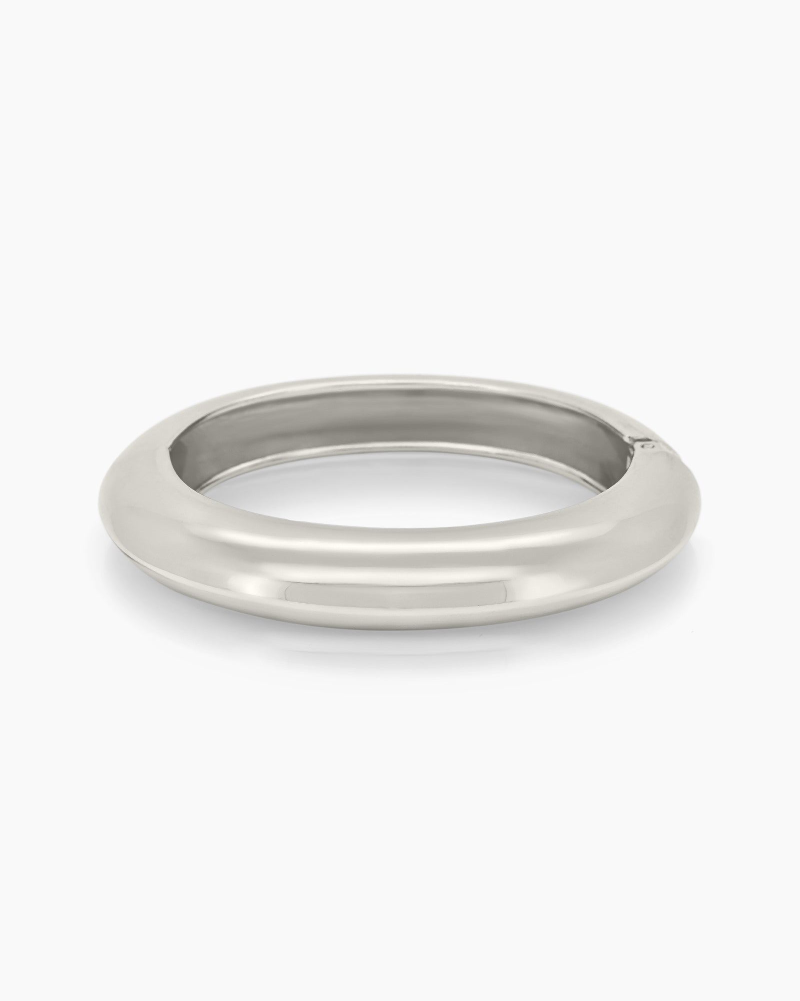 A sculptural silver bangle with a bold, rounded silhouette, high-polish finish, and seamless hinge closure