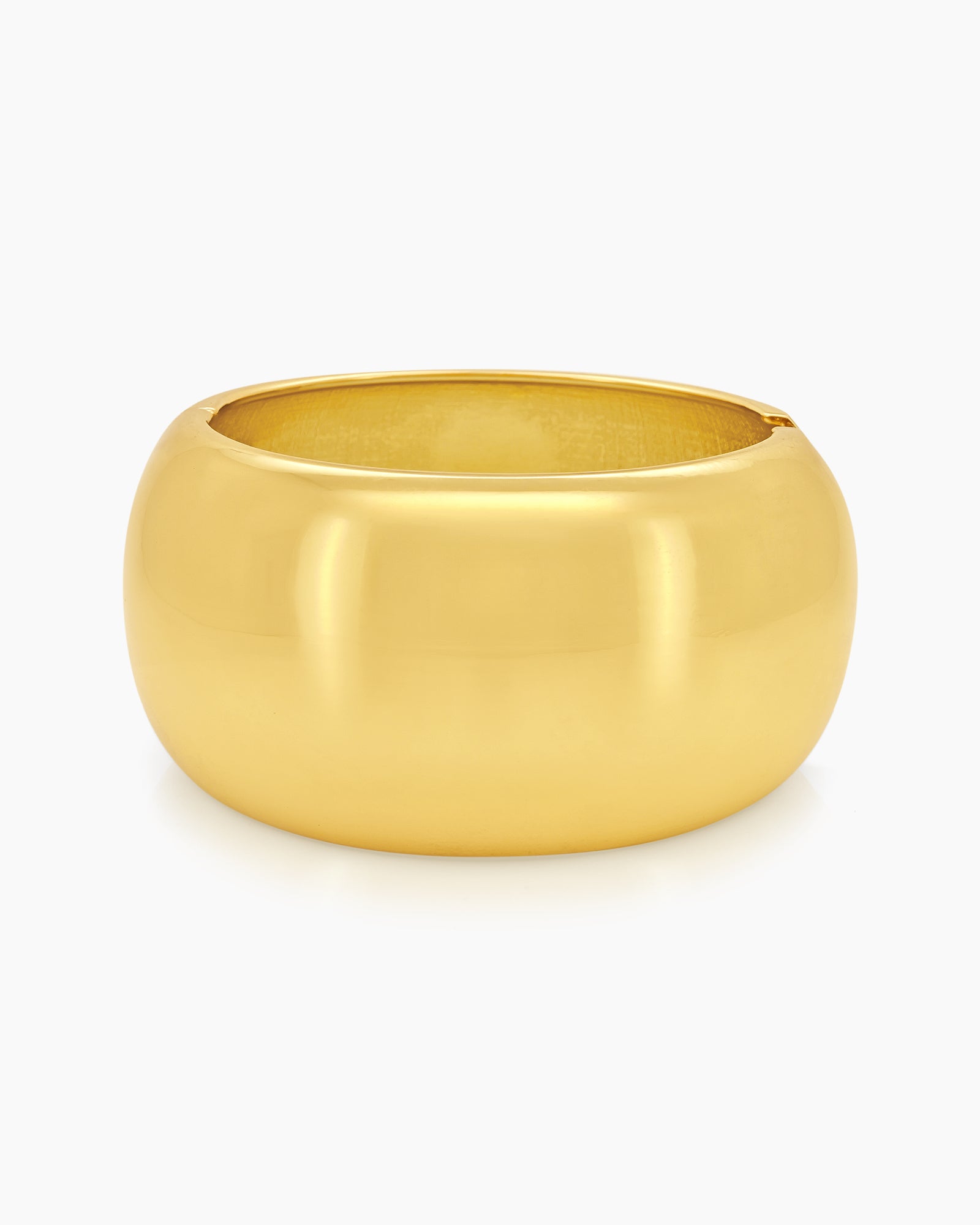 A gold bangle with a wide, mirror-like surface and a curved silhouette for a sleek, modern look