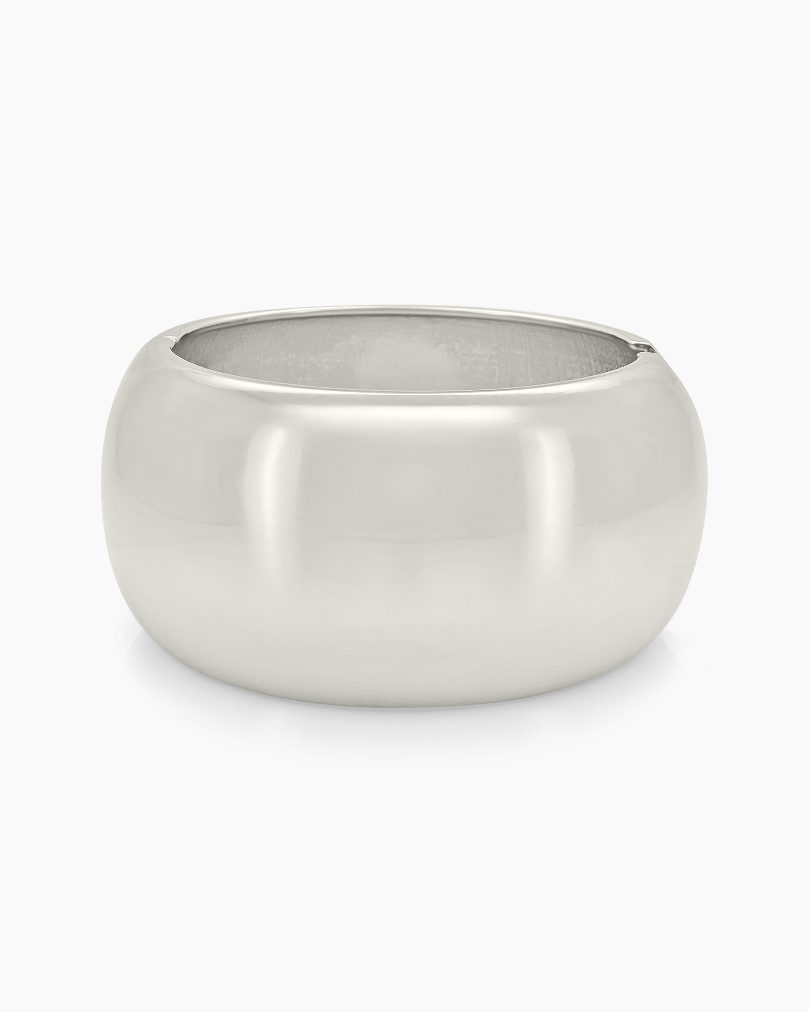 A silver bangle with a wide, mirror-like surface and a curved silhouette for a sleek, modern look