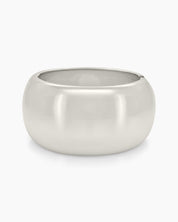 A silver bangle with a wide, mirror-like surface and a curved silhouette for a sleek, modern look