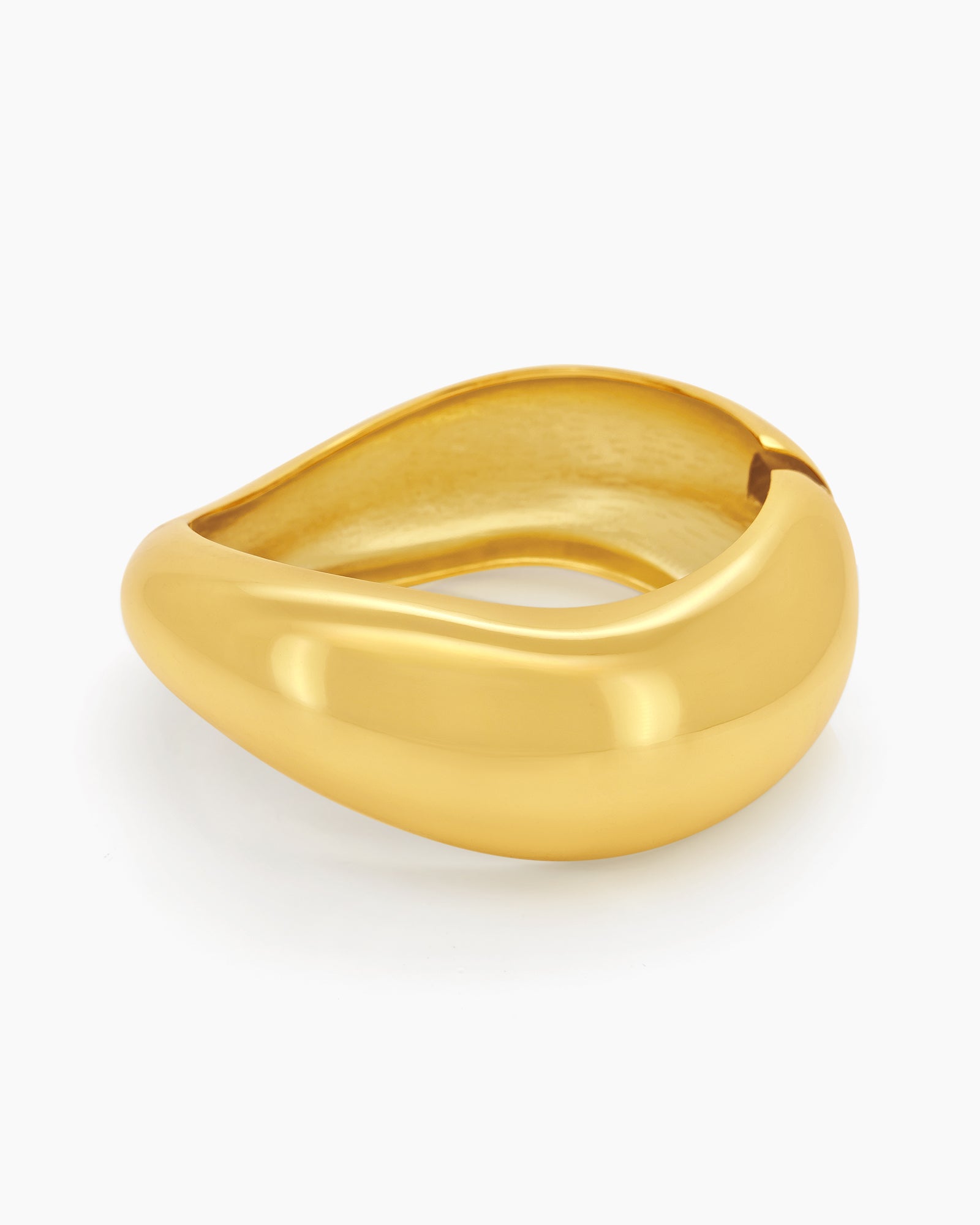 A gold hinged bangle with smooth curves and a fluid, wave-like silhouette for a minimalist focus