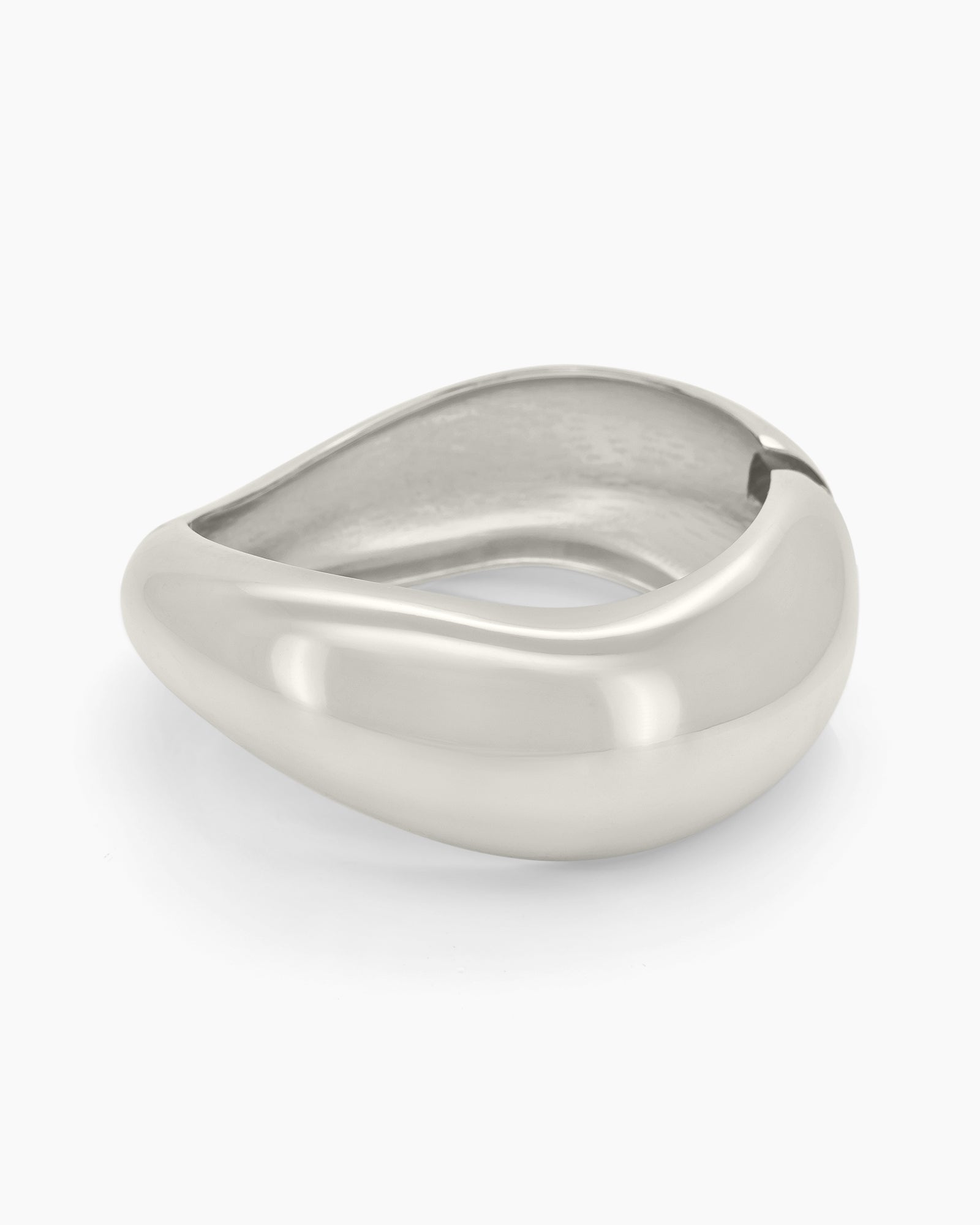 A silver hinged bangle with smooth curves and a fluid, wave-like silhouette for a minimalist focus