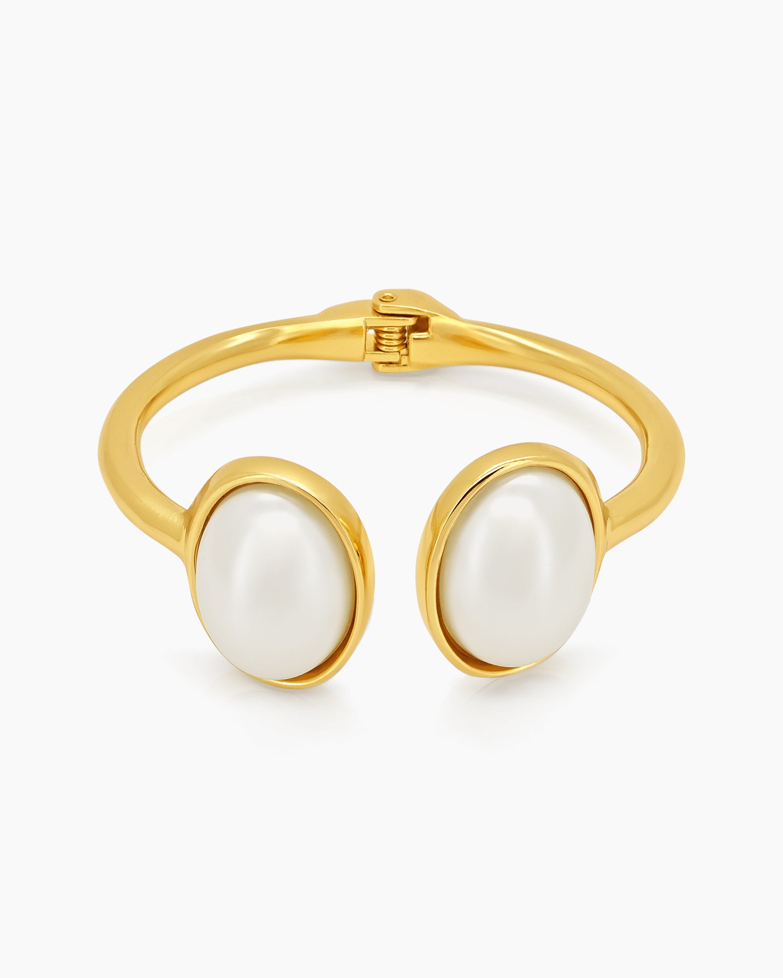 A polished gold cuff with two oversized faux pearls in a glossy frame and a secure hinge closure