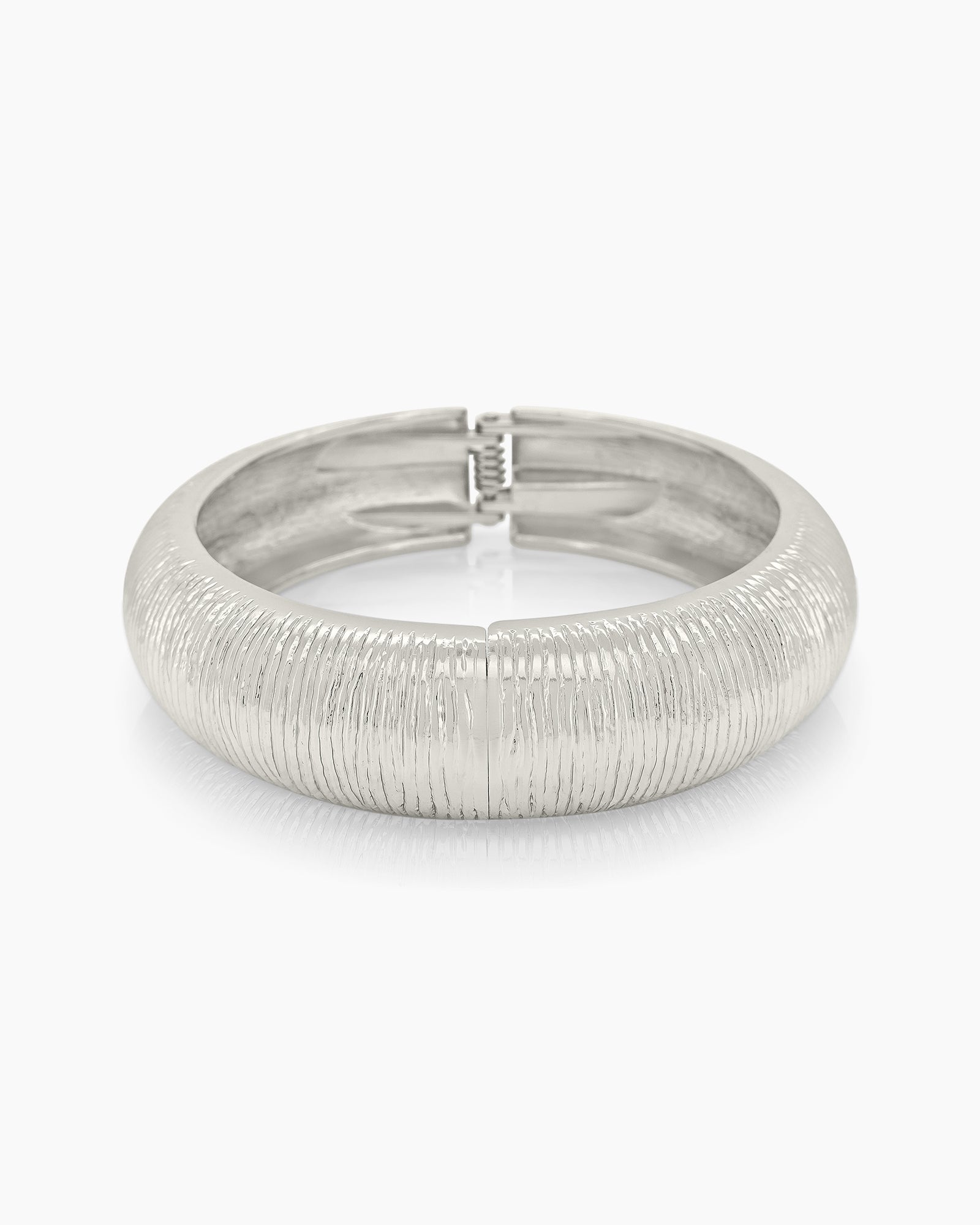 A classic silver bangle with a deeply etched texture, high-shine finish, and a secure hinge clasp
