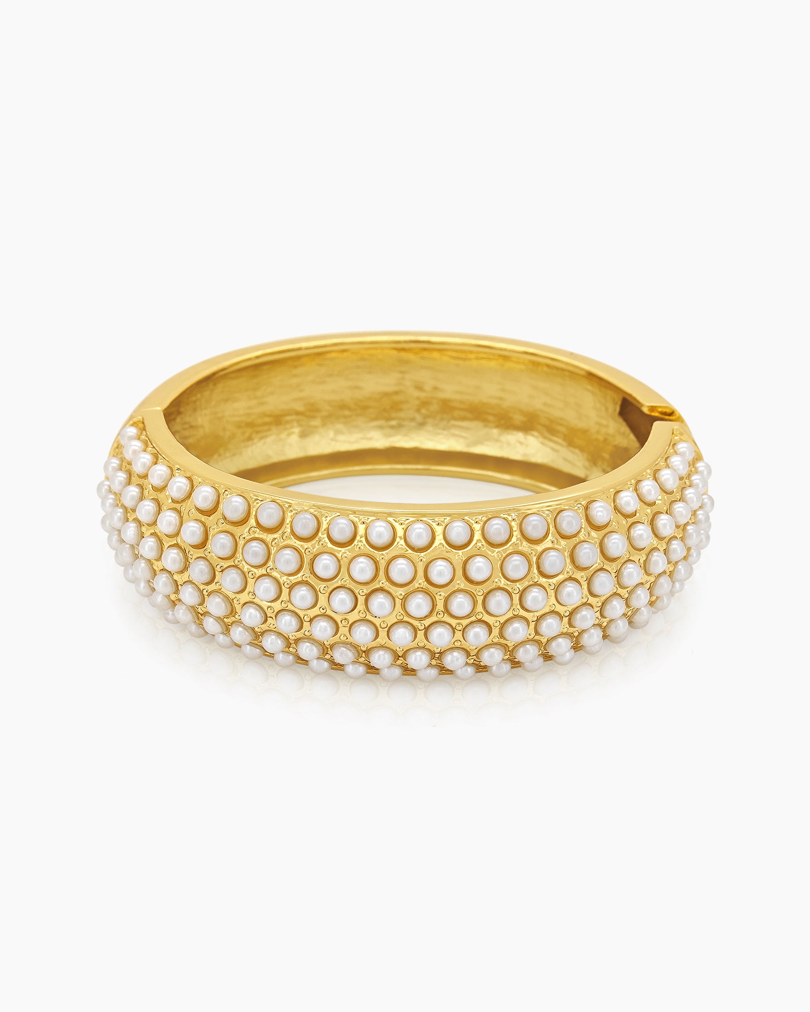 A gold-tone bangle encrusted with rows of tiny faux pearls, creating a soft, sculptural rhythm