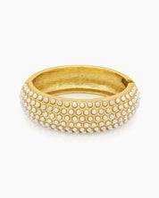 A gold-tone bangle encrusted with rows of tiny faux pearls, creating a soft, sculptural rhythm